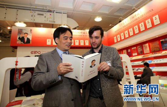  4月14日，中国国际出版集团副总裁陆彩荣（左）在伦敦书展上向一名英国读者介绍《习近平谈治国理政》（繁体中文版）一书。