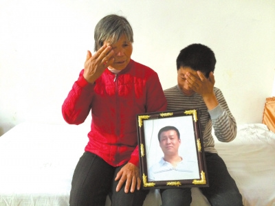 于钢峰的母亲和小儿子捧着其遗像流泪不止。京华时报记者钱卫华摄