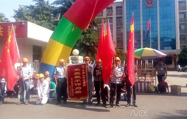 19日上午,张蓬冲在内的数十位工友在到平顶山市公安局门口送“不作为”锦旗。图片由受访者提供 19日上午,张蓬冲在内的数十位工友在到平顶山市公安局门口送“不作为”锦旗。图片由受访者提供
