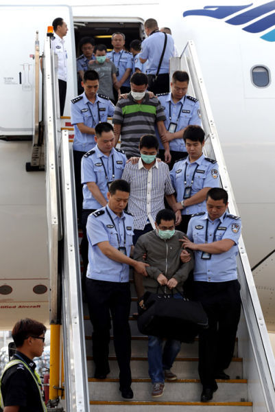 6月21日，公安人员在北京首都机场押解境外在逃经济犯罪嫌疑人走下飞机。