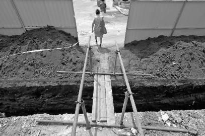 施工方为居民用木板搭建小桥，以便于通行 新文化记者 吴廷 摄 