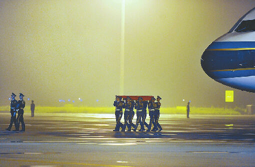 在礼兵的护送下，覆盖着中华人民共和国国旗的烈士灵柩，被缓缓抬下飞机。 本版照片均由记者郭尧 摄