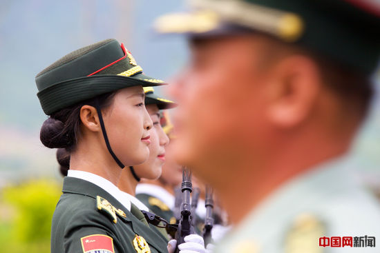 2015年8月14日，北京某阅兵训练基地，一名军官从正在为抗战胜利70周年阅兵式训练的三军仪仗队女兵身前走过。中国网记者 吴闻达 摄