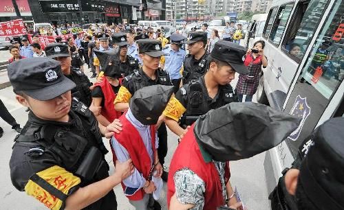 身着鲜红色囚服、拖着沉重的脚镣，7名盗抢嫌犯日前在特警的押解下，到贵阳闹市指认现场，引发群众围观。