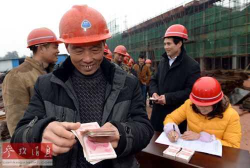 资料图片：2014年1月11日，农民工钟弼桂（左二）在江西省高安市工业园区的一个建筑工地上点数领到的工资。新华社