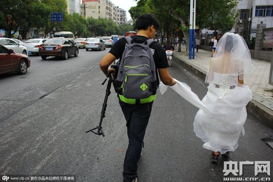 　陈女士的婚礼摄像师为其托住婚纱 