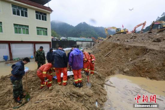 灾害现场又一具遗体被找到，负责搜救的消防和武警救援队员在现场脱帽向遇难者致哀