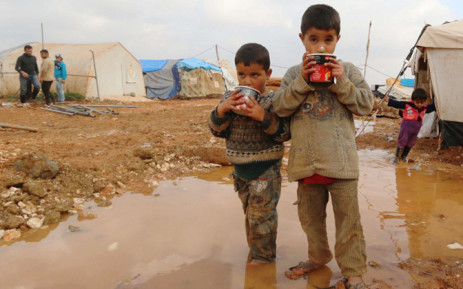 FILE: Displaced Syrian children stand in muddy water after heavy rains in the Bab Al-Salama. Picture: AFP