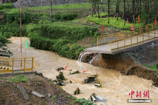资料图：6月5日凌晨3时至6时，贵州省雷山县遭受暴雨袭击，造成县城部分街道及丹江、大塘等乡镇农田、民房、建筑工地等受灾。图为雷山至大塘快速通道工地过桥被洪水冲断。 中新社发 杨承鸿 摄