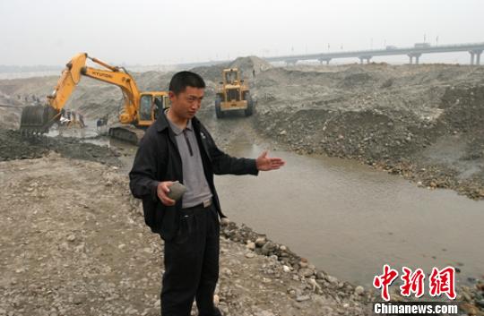 2005年彭山岷江施工过程中发现几锭银锭，工人师傅手拿银锭介绍情况。（资料图） 刘忠俊 摄