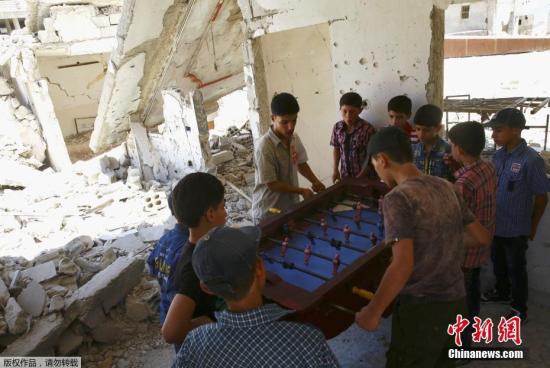 当地时间2017年6月26日，叙利亚反对派控制区杜马，男孩在废弃的建筑内玩桌上足球庆祝开斋节。