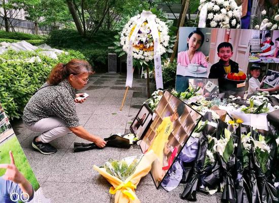 纵火悲剧发生后，各界人士纷纷送来鲜花悼念，遇难者朱小贞的母亲一直在女儿和孩子们的遗像前布置鲜花（于楚众摄）