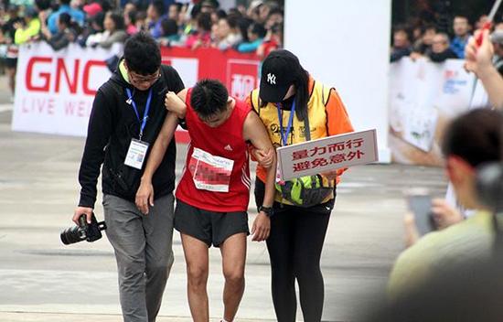 2015年上海国际马拉松赛，志愿者搀扶力竭跑友。  东方IC 资料图