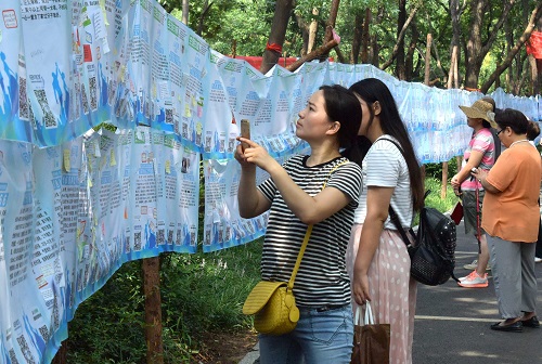 资料图：一名市民在济南千佛山公园举行的“七月七相亲大会”上用手机记录相亲信息。新华社记者 徐速绘 摄
