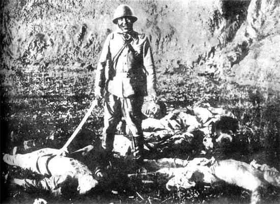 ▲一名日军官兵在砍杀数名中国人后，提起一颗血淋淋的人头，让人为其拍照留念。选自《罪证：日军镜头中的侵华记录》