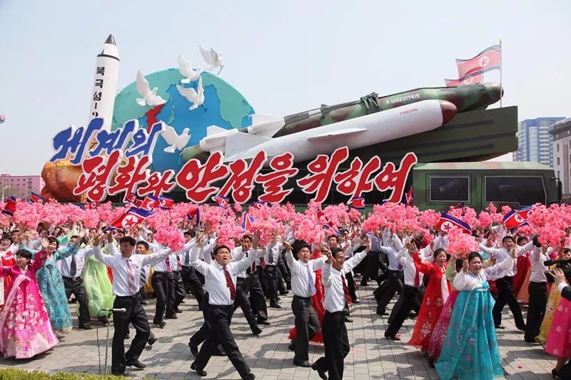 △4月，朝鲜举行阅兵后的民众游行。花车上有朝鲜的导弹模型，在导弹旁边是几只和平鸽。下面的文字是“为了世界的和平和安定”。