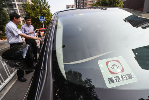 资料图片：北京东三环一小区外，一家网络约车公司的司机为约车的乘客打开车门（2016年7月28日摄）。新华社记者 罗晓光 摄