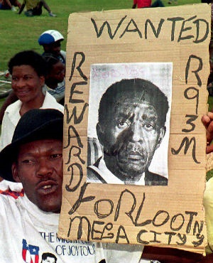 An ANC supporter holds an anti-Lucas Mangope poster and a mannequin leg at a rally in Mmabatho 13 March 1995. (File, AFP) 