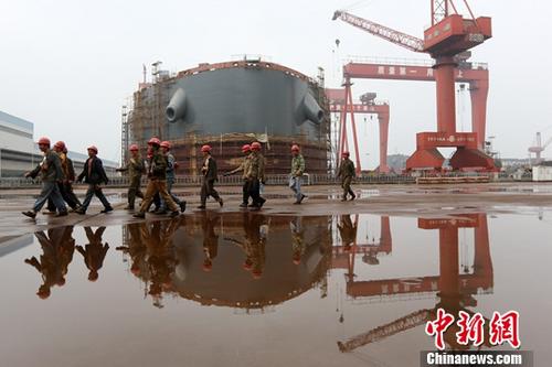 图为江苏泰州一家造船厂内，工人从正在建造的船前经过。（资料图片）中新社记者 泱波 摄