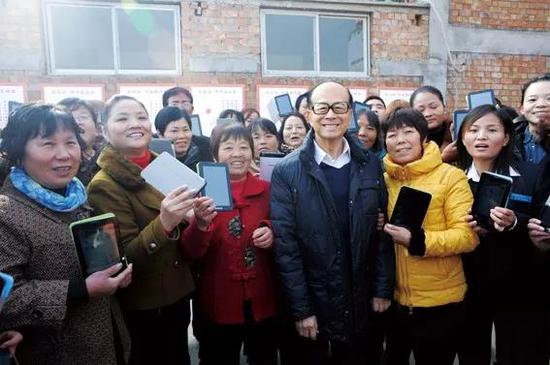 2013年11月19日，李嘉诚在西安咸阳大石头村，出席“展璞计划”启动仪式，女村官们手举该项目资助的平板电脑与李嘉诚合影   图 / 本刊记者 方迎忠