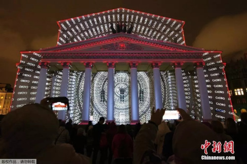 资料图：当地时间2019年9月21日，俄罗斯莫斯科举办第九届“光之环”国际灯光节。人们在莫斯科大剧院前欣赏灯光秀表演。