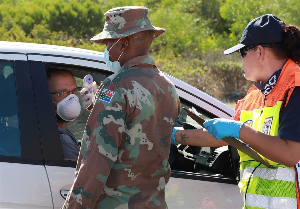 A SANDF medic shows the temperature of a motorist to him with a thermometer at a roadblock on April 26 in Cape Town.