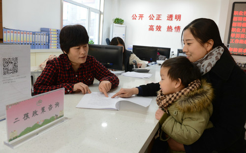 资料图片：社区工作人员（左）为居民介绍“全面二孩”政策（2016年1月14日摄）。新华社记者 王晓 摄