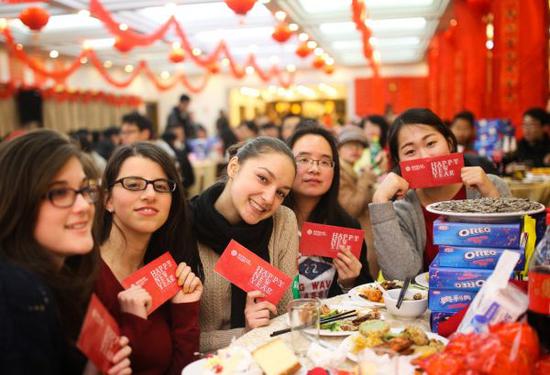 在华外国留学生们手拿红包在学校食堂过年。新华社
