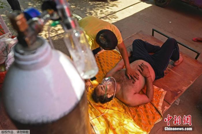当地时间4月26日，印度加兹阿巴德，一名新冠患者在路边搭建的帐篷内吸氧。